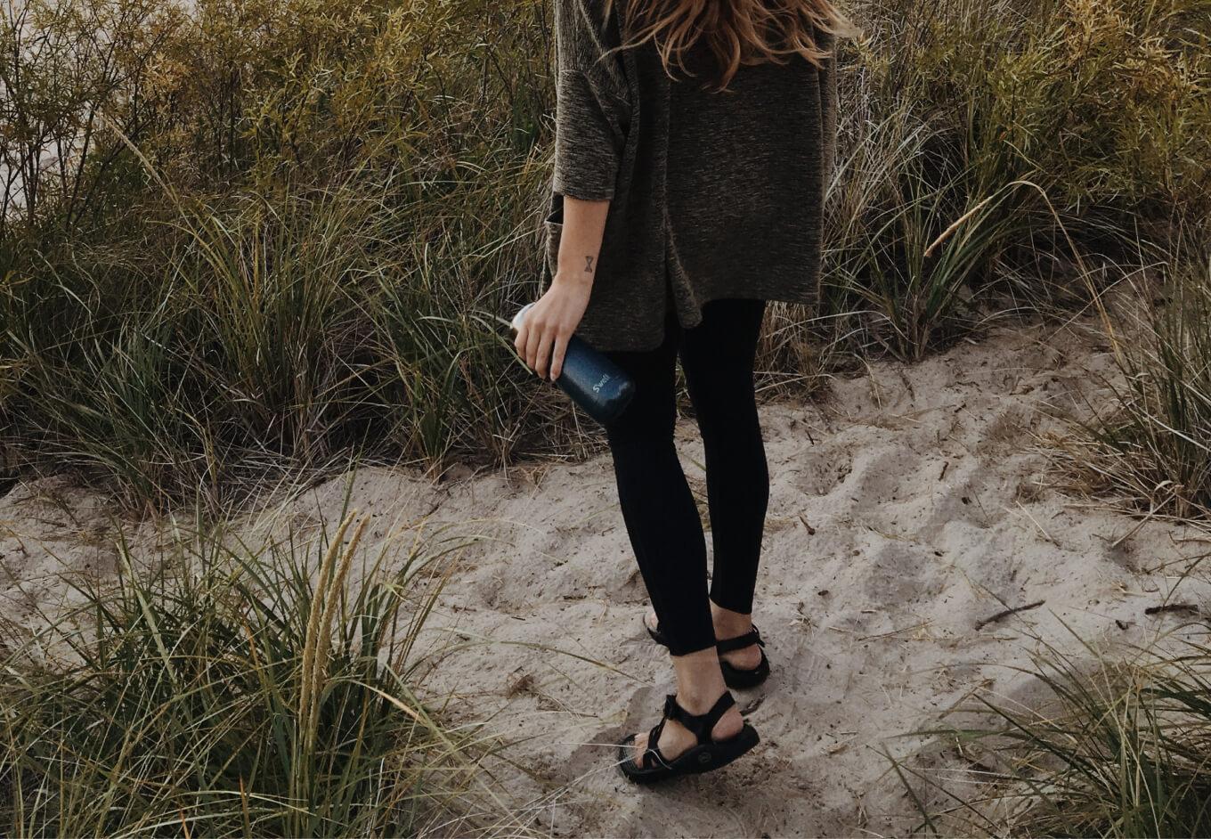 Woman on a beach holding a Swell bottle